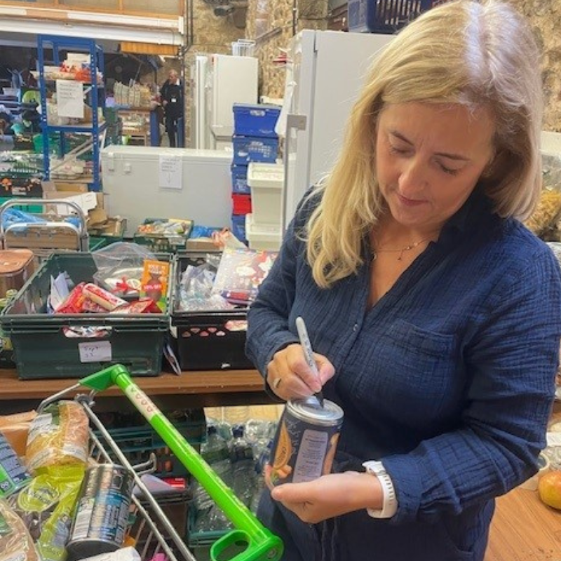 Woman marking a tin in a food bank