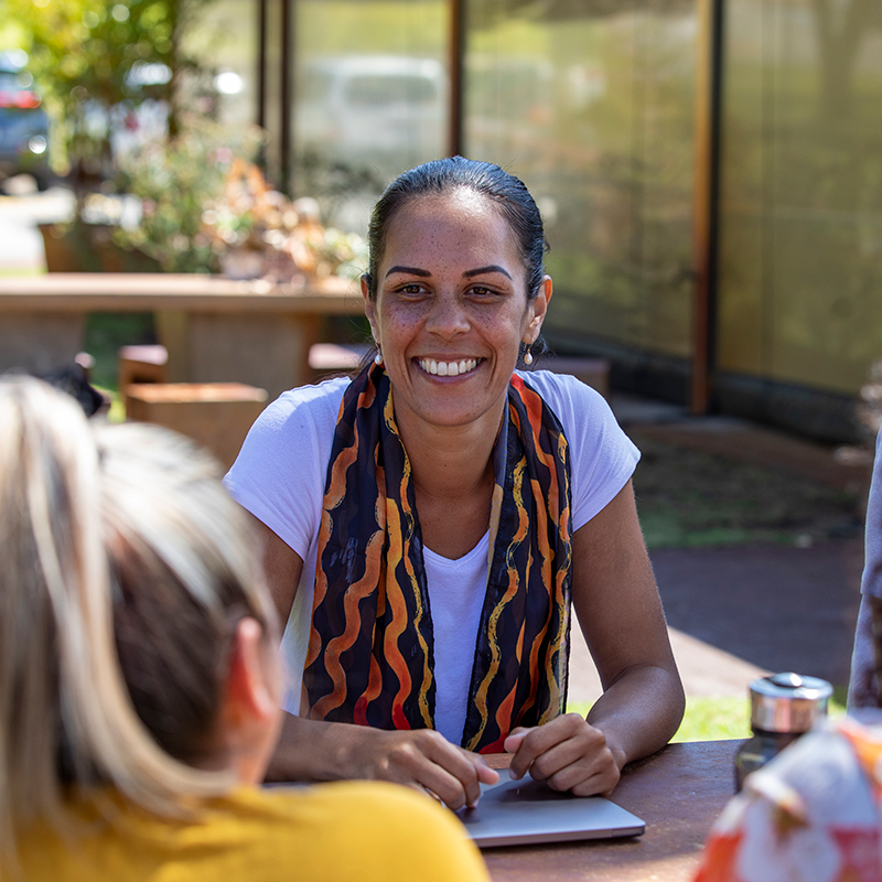 Close-up of young adults sitting together outdoors in the sun.
