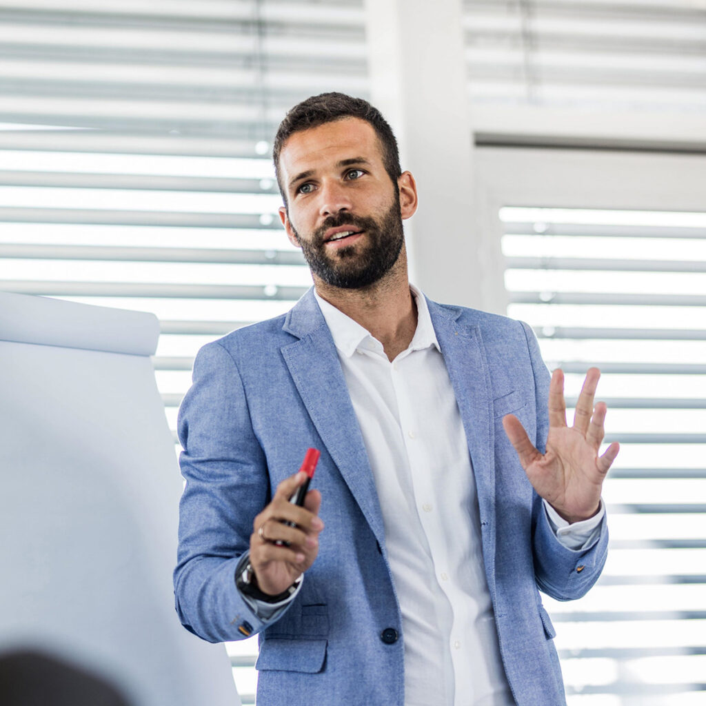 Trainer speaking in front of a group of learners in a meeting room. 