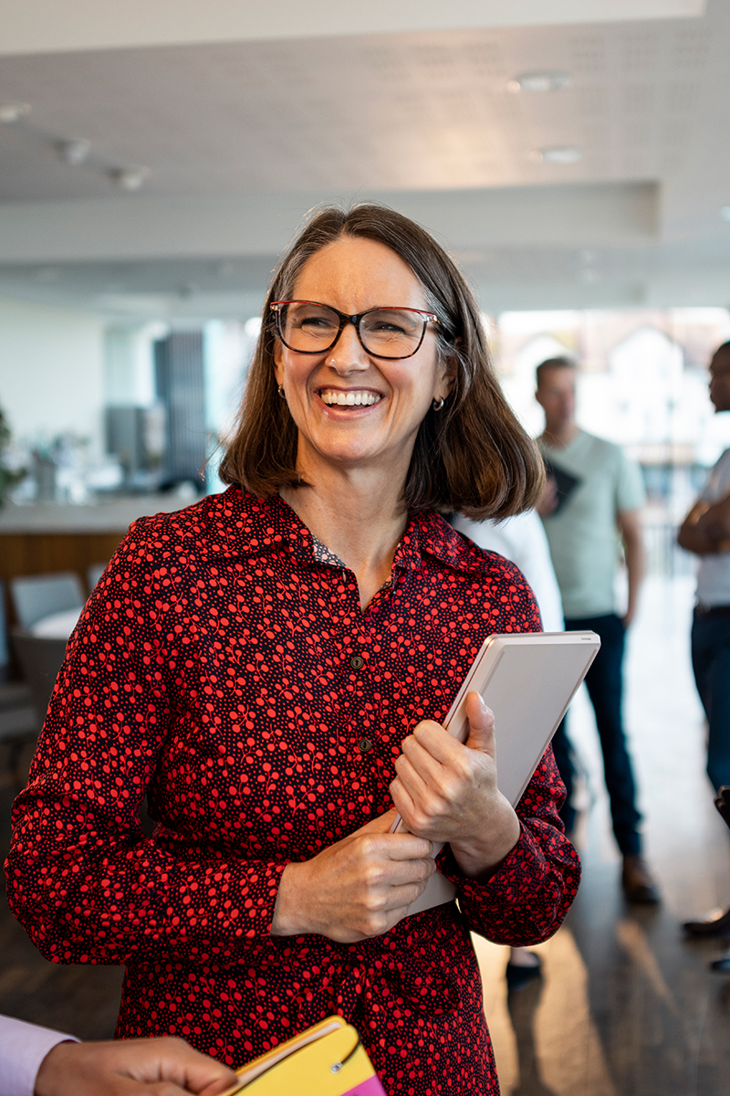 Businesswoman smiling whilst taking to her colleagues in an office environment. 