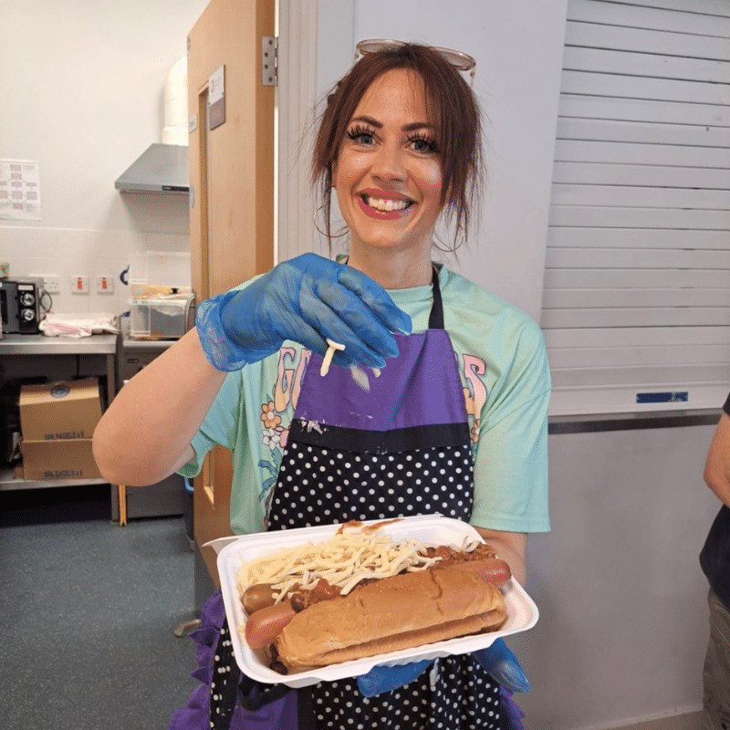 Hannah Parnell holding a hot dog in takeaway packaging for her volunteering days