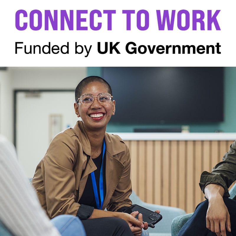 Smiling programme participant looks to her work coach who is not in shot.